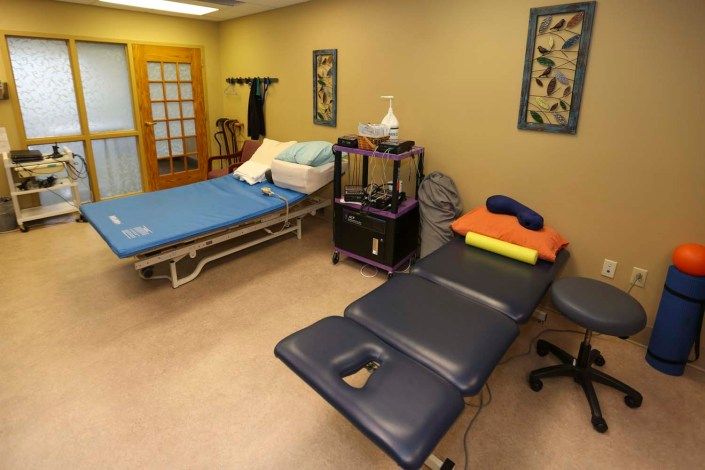A therapy room with a massage table and treatment bed.