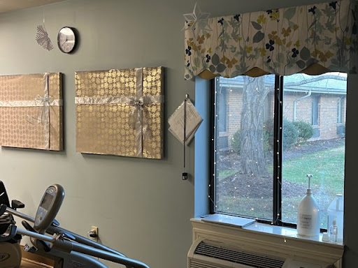 A cozy room featuring modern art pieces, a window with floral curtains, and a clock on the wall.