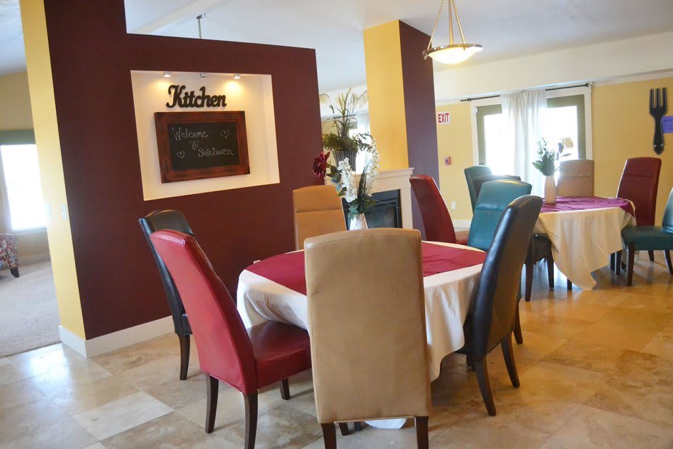 A cozy dining area with a set table and colorful chairs.