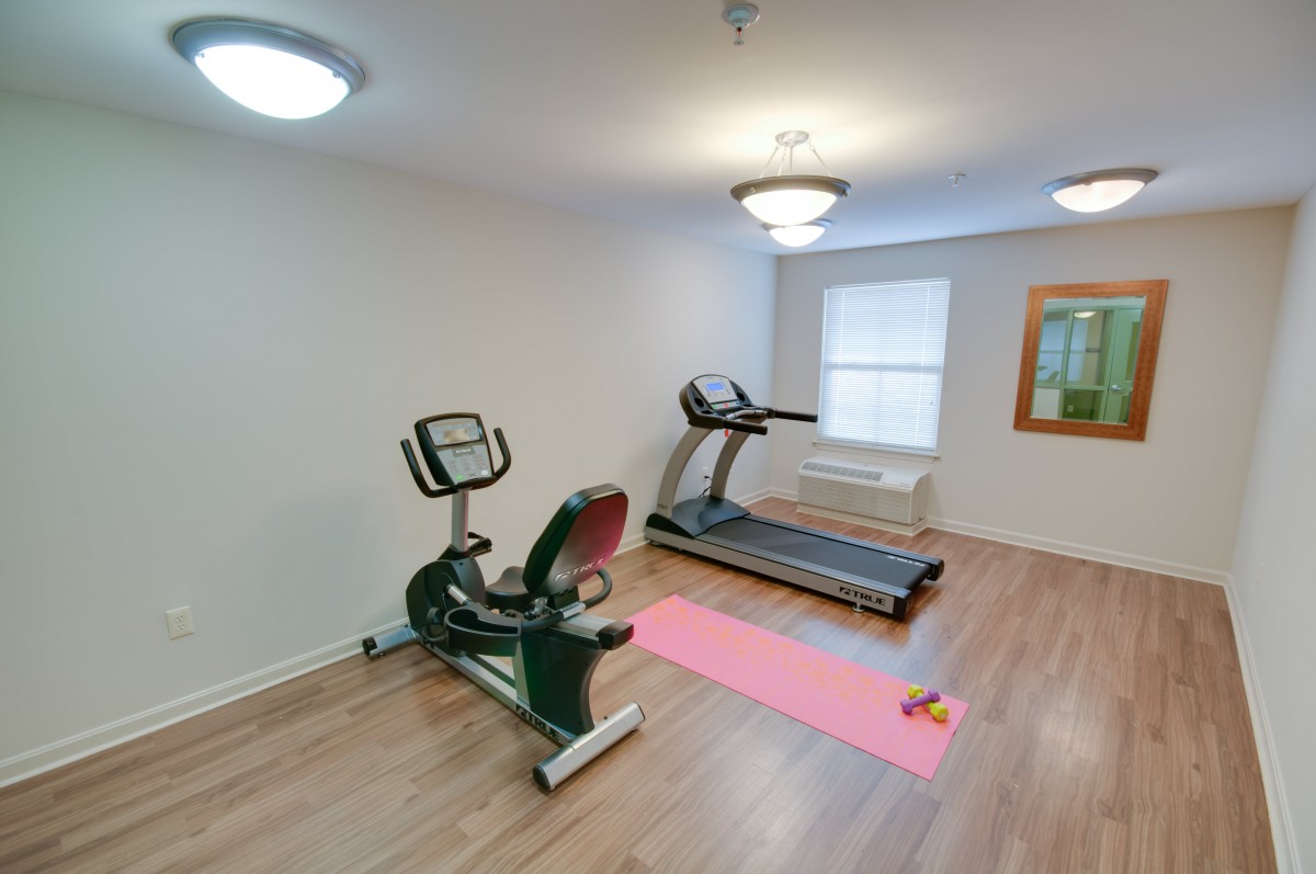 A small home gym with a treadmill, stationary bike, and yoga mat.
