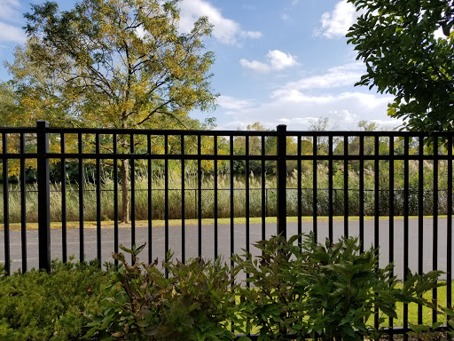 A view of a fenced area with trees and a clear sky in the background.