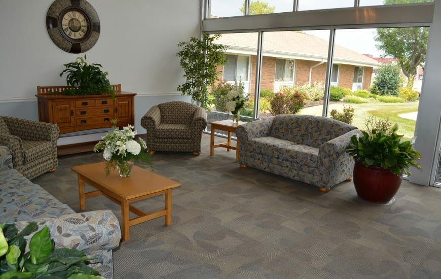 A cozy living room with sofas, chairs, and a coffee table adorned with plants and flowers.