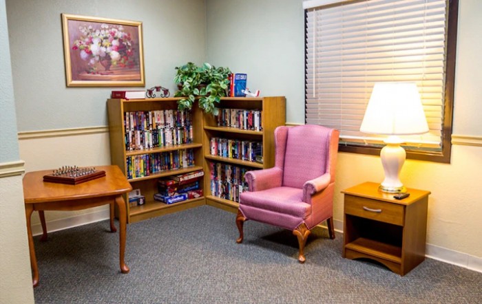 Cozy reading nook with a bookshelf, armchair, and lamp.