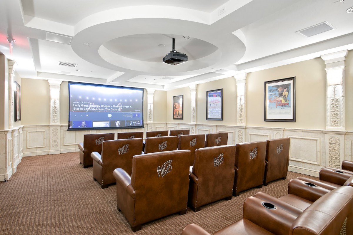 A cozy home theater with rows of plush leather seating, a large projection screen, and elegant interior lighting.