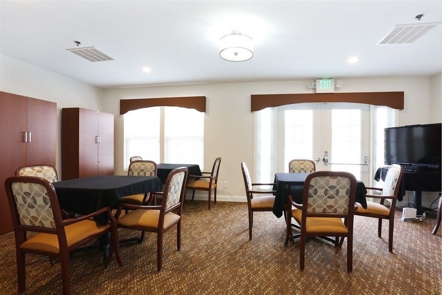 A well-lit dining area with round tables and upholstered chairs.