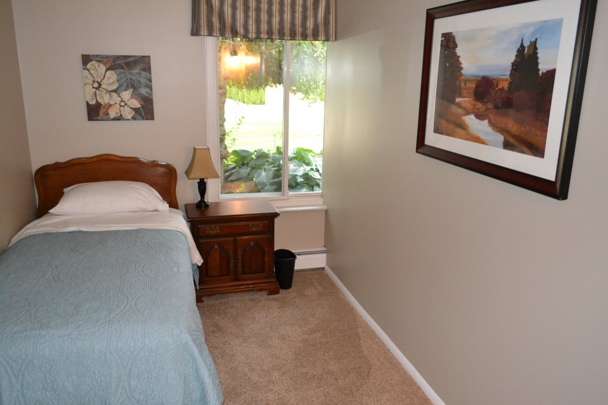 A cozy bedroom with a single bed, nightstand, and window view.