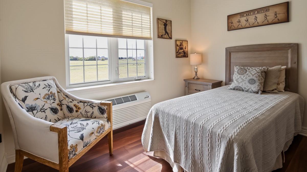 A cozy bedroom featuring a single bed, a chair, and a window overlooking a scenic view.