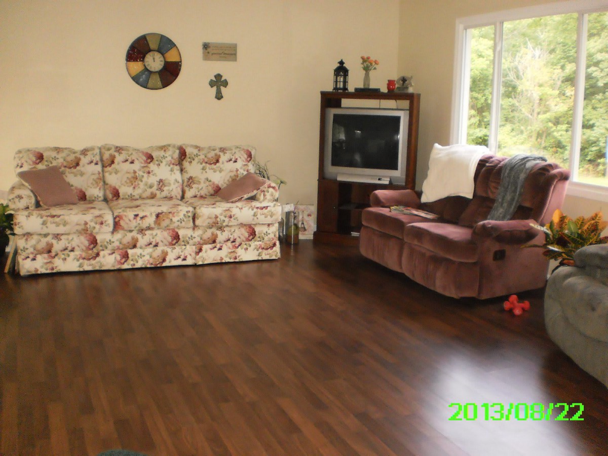 Cozy living room with a floral couch and armchair, featuring a television and wooden flooring.