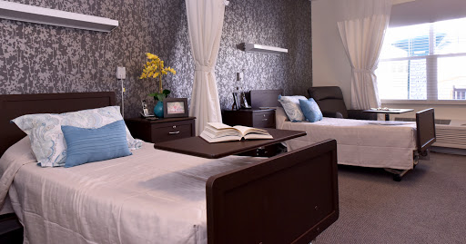 A serene and modern hospital patient room, featuring two beds with comfortable linens, soft lighting, and decorative elements for a calming atmosphere.