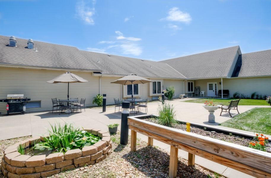 A sunny courtyard with outdoor seating and garden beds in a landscaped area.