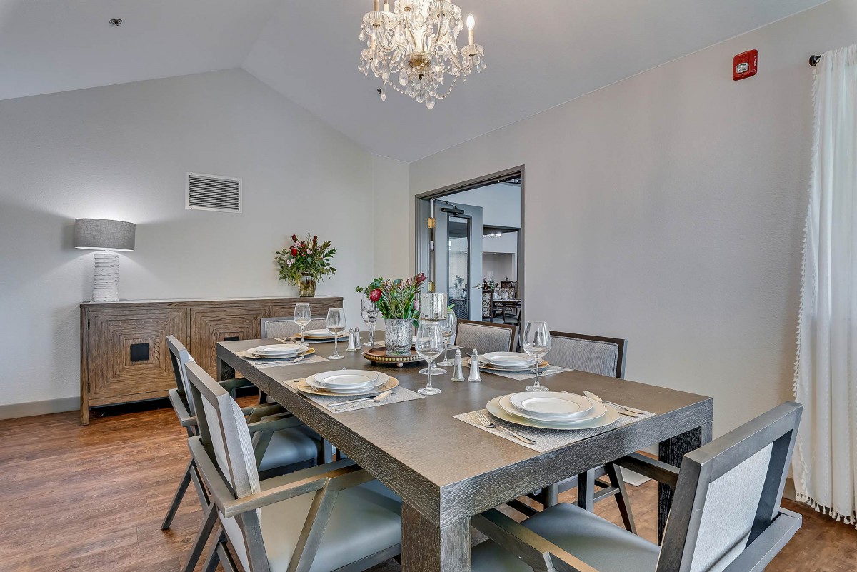 A modern dining room with a stylish table setting and a chandelier.