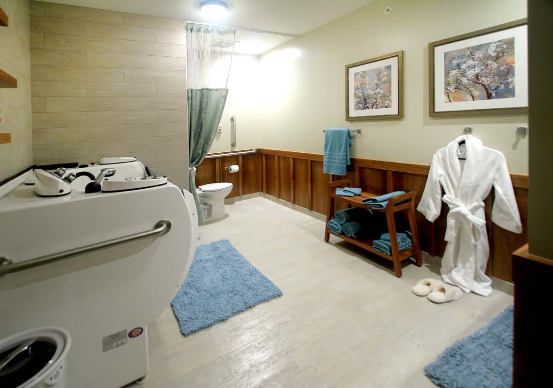 A modern bathroom with a bathtub, toilet, and neatly arranged towels and robe.
