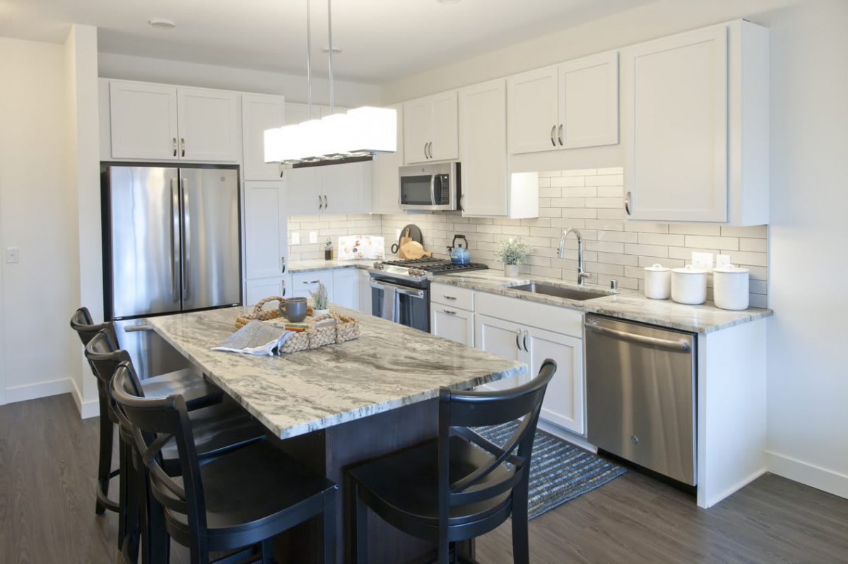 A modern kitchen with an island, featuring stainless steel appliances and white cabinets.
