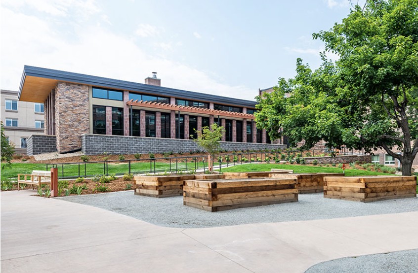 A modern building with a courtyard featuring wooden benches and greenery.