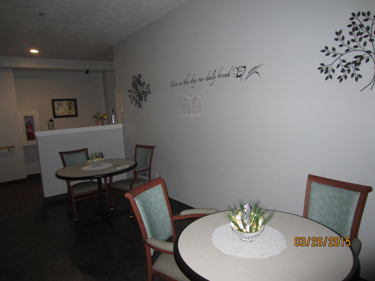 A cozy seating area with tables and chairs, adorned with wall decorations and plant centerpieces.