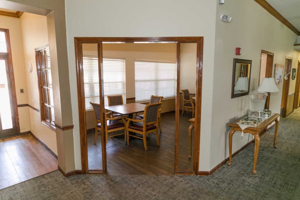 A cozy dining area with a wooden table and chairs surrounded by large windows.