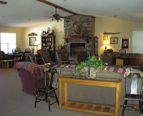 A cozy living room with a stone fireplace and various furnishings.