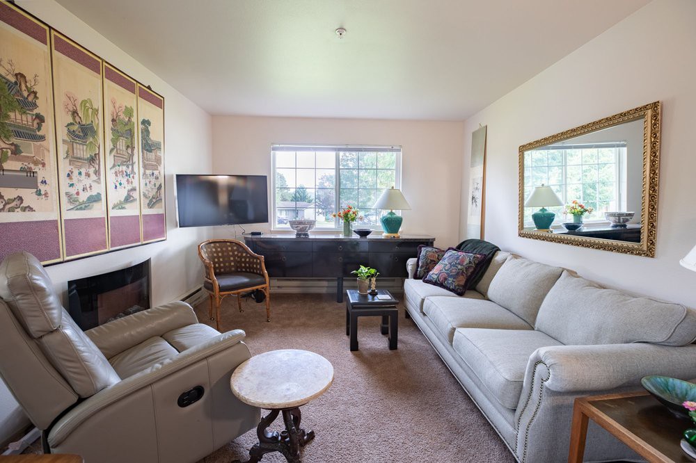 A cozy living room with a sofa, television, and large window providing natural light.