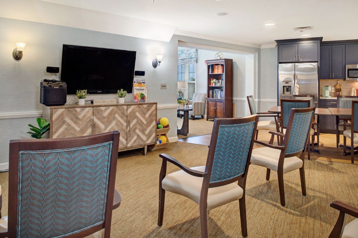 A modern living room setup with chairs facing a television and a bookshelf in the background.