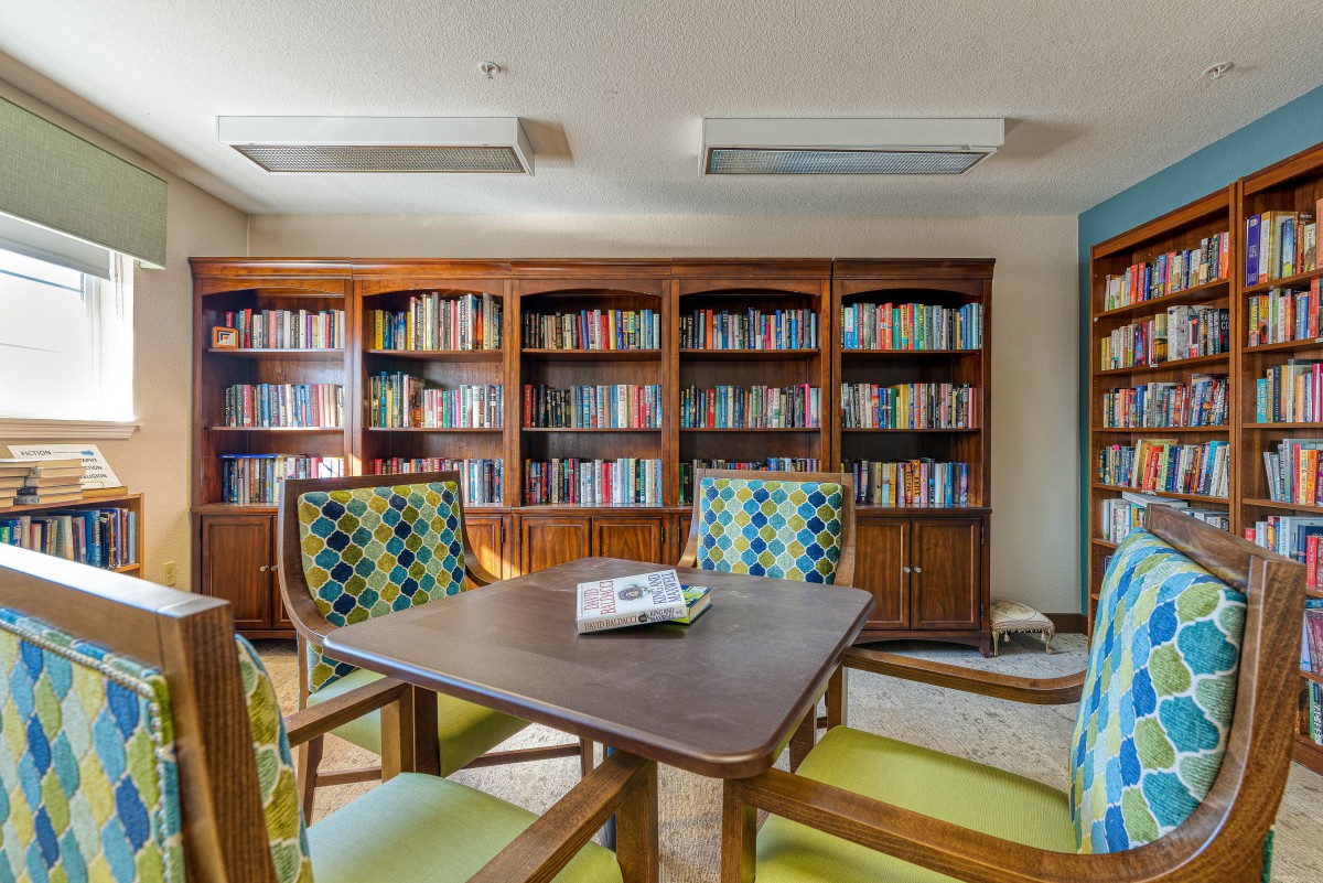 A cozy library with bookshelves, a table, and chairs for reading.