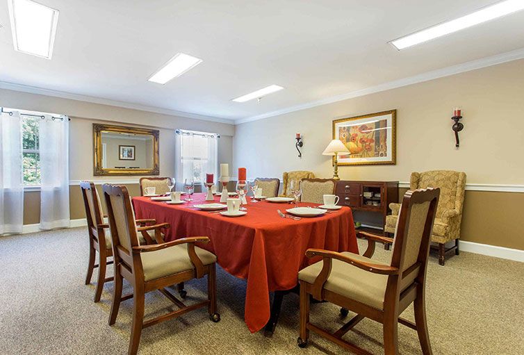 A well-arranged dining room featuring a table with a red tablecloth, surrounded by chairs.