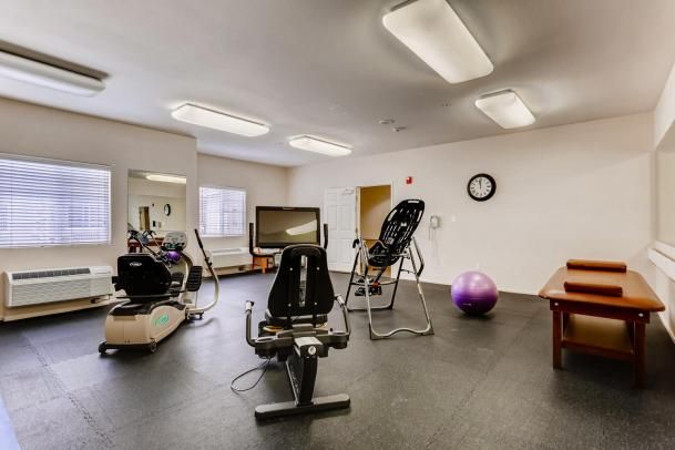 A small gym with various exercise equipment, including an inversion table and an exercise ball.