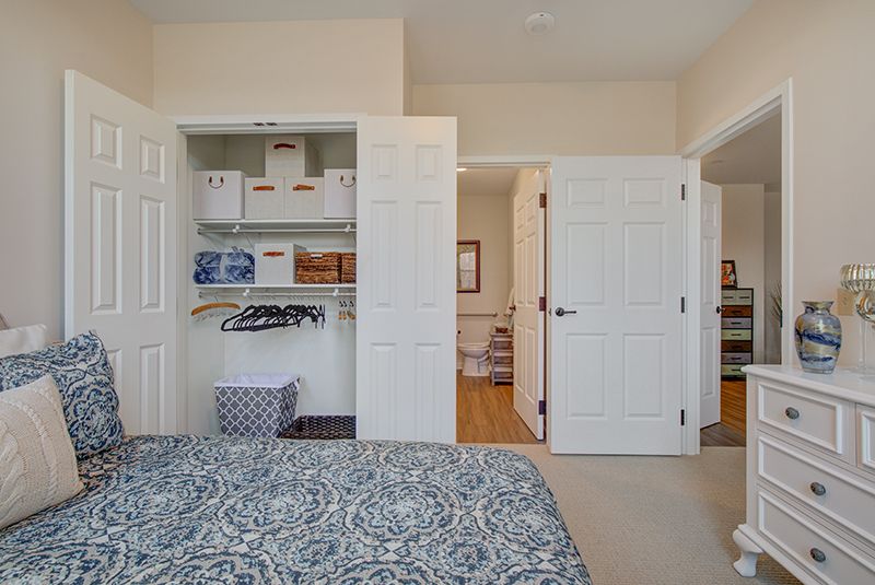 A well-organized bedroom with an open closet displaying neatly arranged boxes and hangers.