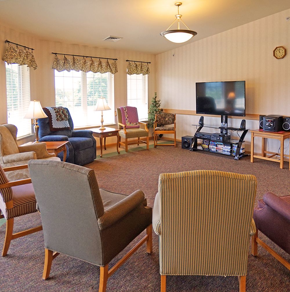 A cozy community living room with comfortable chairs arranged around a television.