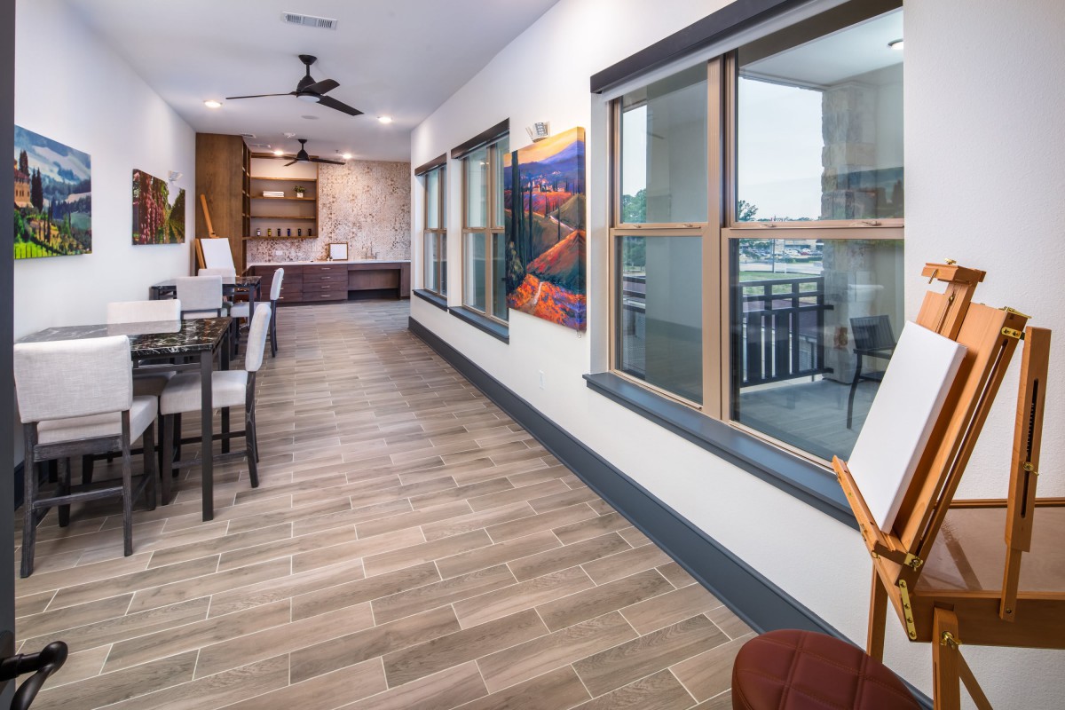 A modern open-concept kitchen and dining area with wood flooring, large windows, and colorful artwork.