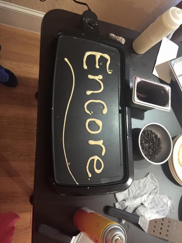 The word 'Encore' written with pancake batter on a griddle.