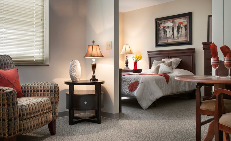 A cozy bedroom with a neatly made bed, warm lighting from table lamps, and tasteful decor.
