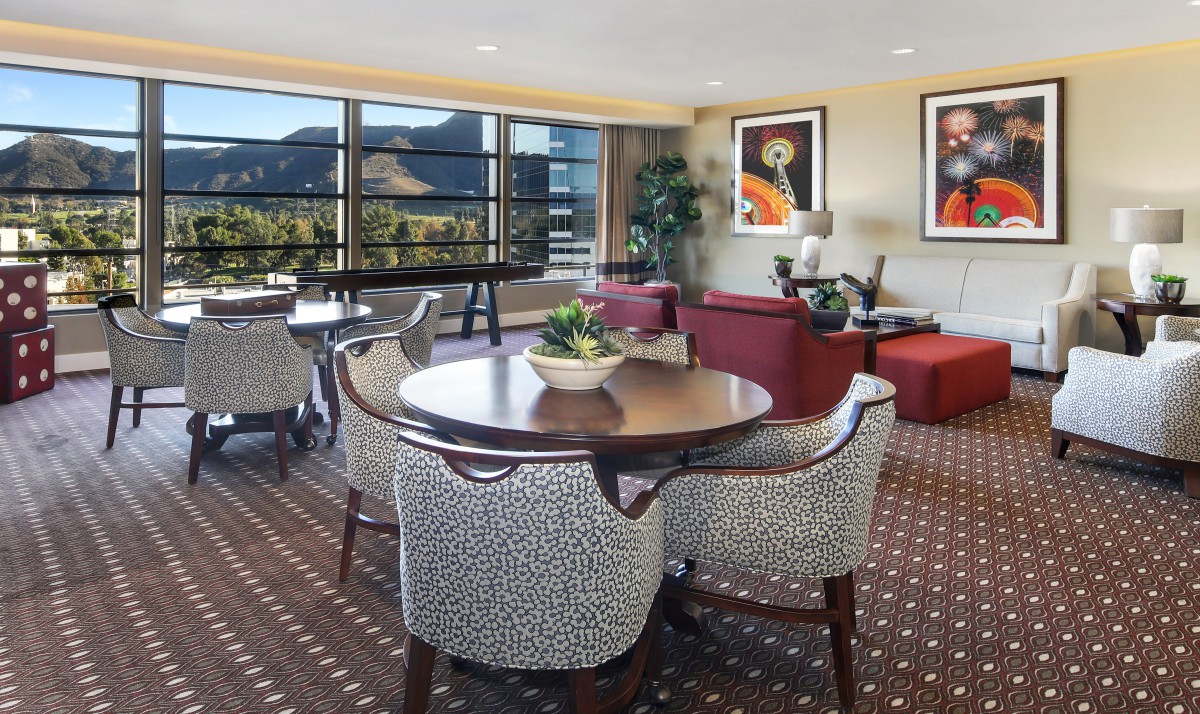 A stylish living room with a dining table and chairs, featuring a large window with a scenic mountain view.