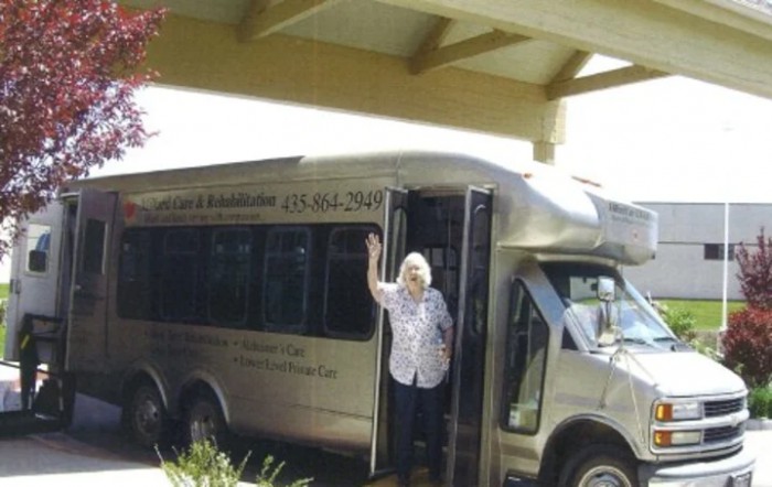 A person standing at the entrance of a bus parked under a structure.