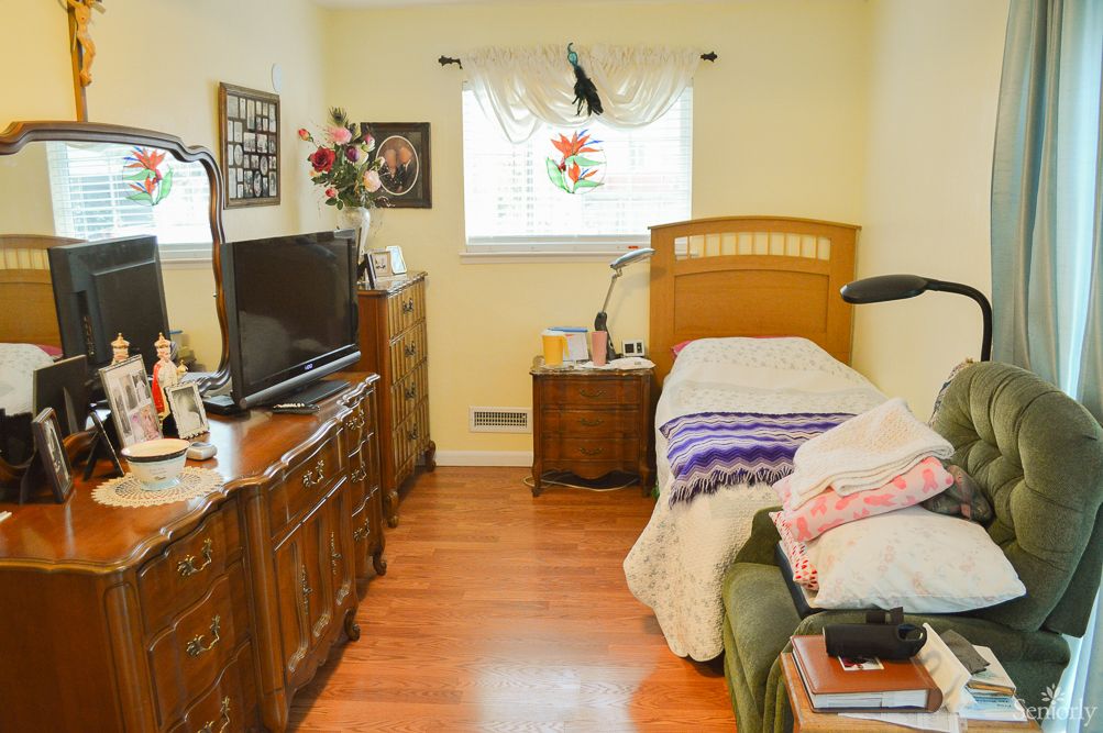 A cozy bedroom with a single bed, television, and wooden furniture.
