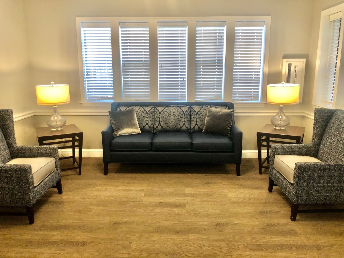 A cozy living room with a dark sofa, two armchairs, and soft lighting from lamps on side tables.
