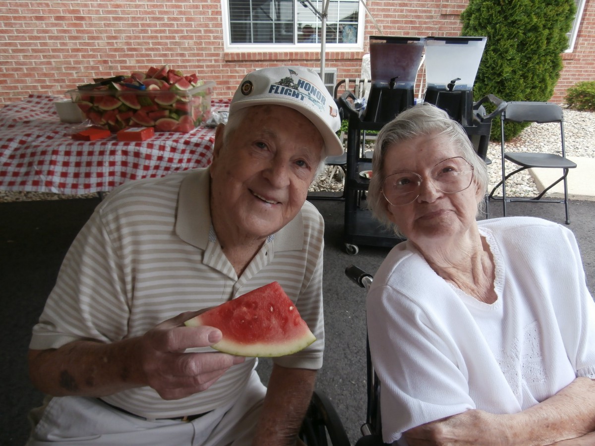 An elderly couple enjoying a slice of watermelon together outdoors.