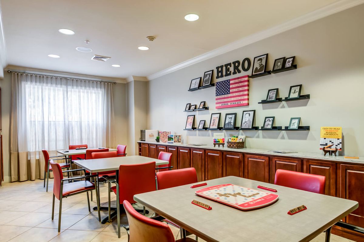 A dining area with red chairs and tables, featuring a wall display of photographs and an American flag.