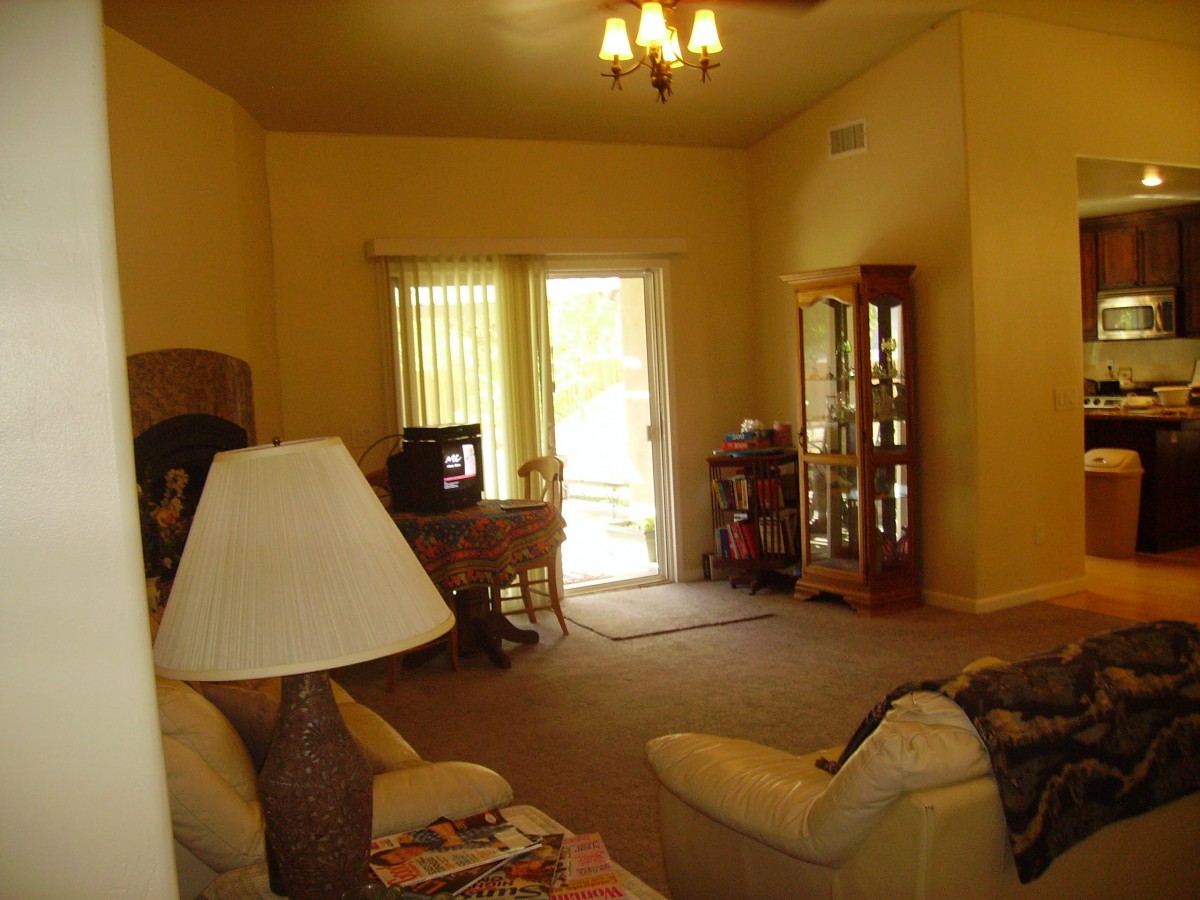 A cozy living room with a sofa, lamp, television, and a cabinet near the window.