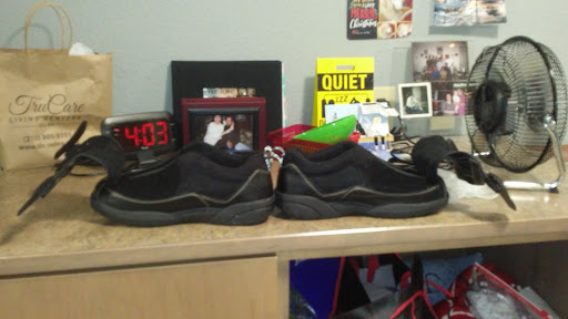 A pair of black sneakers placed on a cluttered desk.