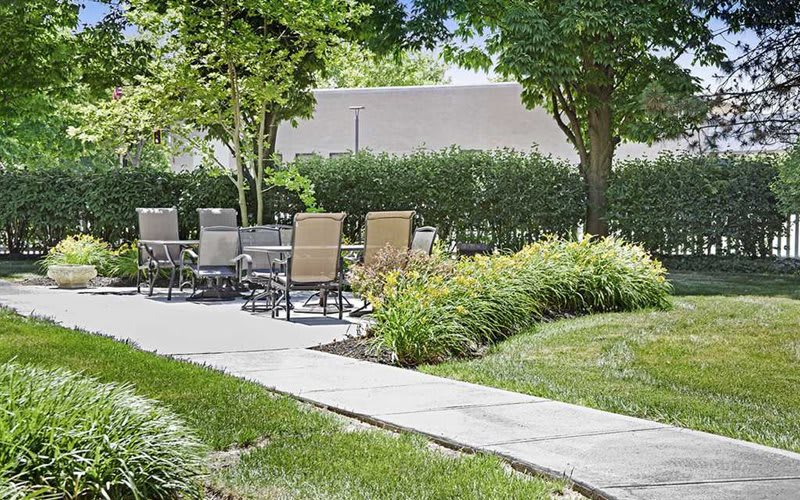 A tranquil garden scene with outdoor seating and lush greenery.