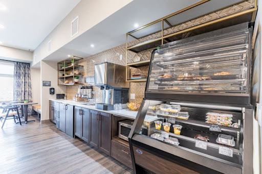 A modern cafe kitchen featuring a sleek bakery display and a coffee station, designed for efficiency and style.
