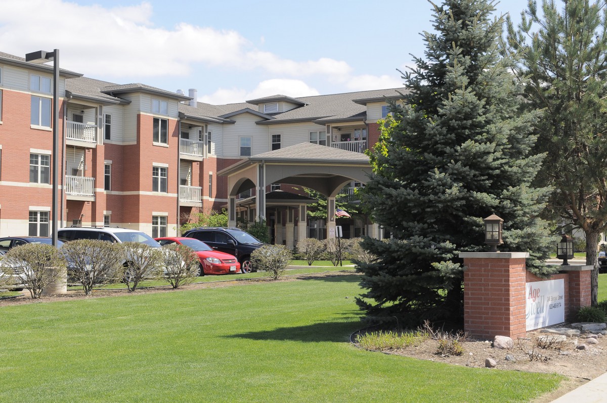 A modern residential building with well-maintained landscaping and parked cars.