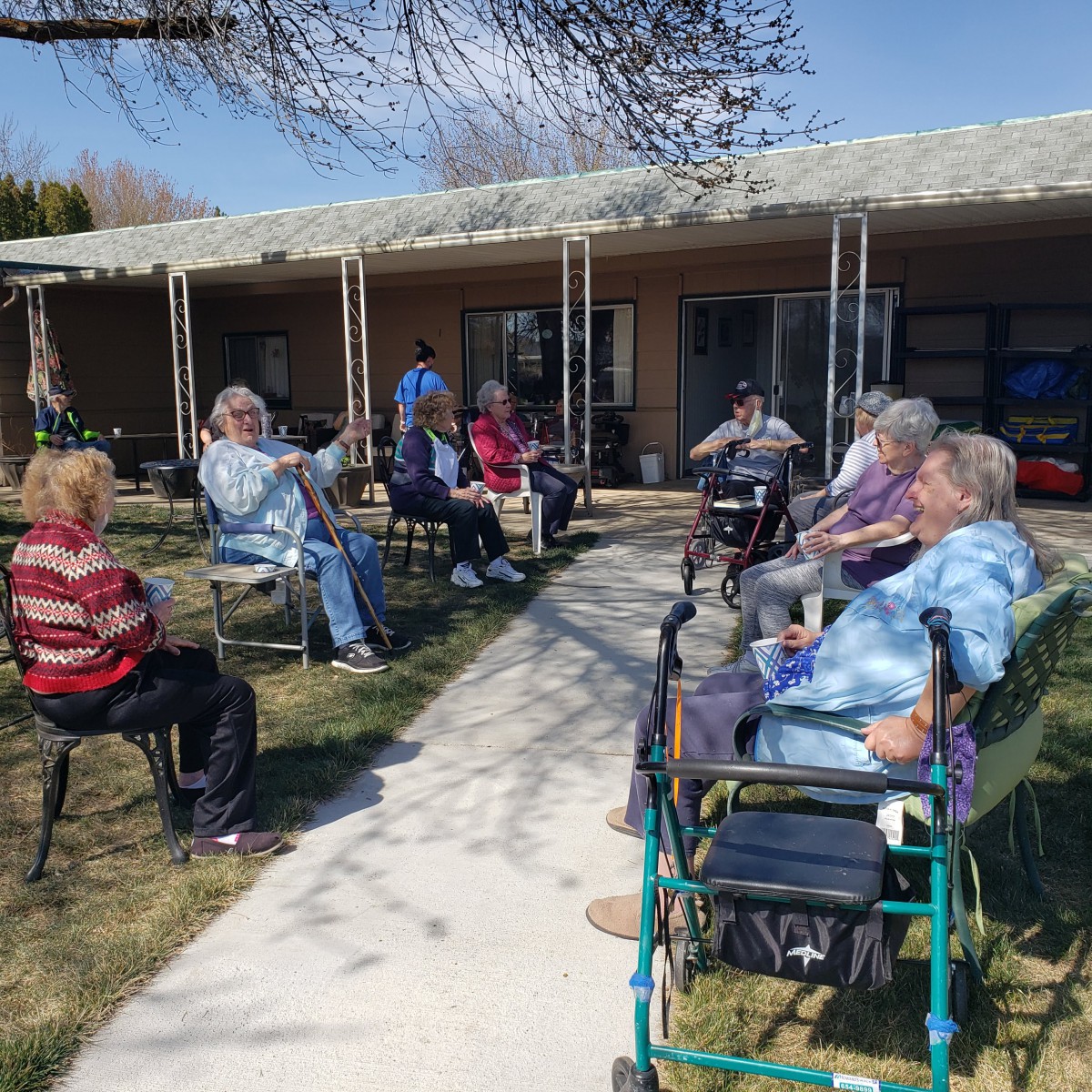 A group of seniors sitting outside in a sunny courtyard, enjoying conversation and fresh air.
