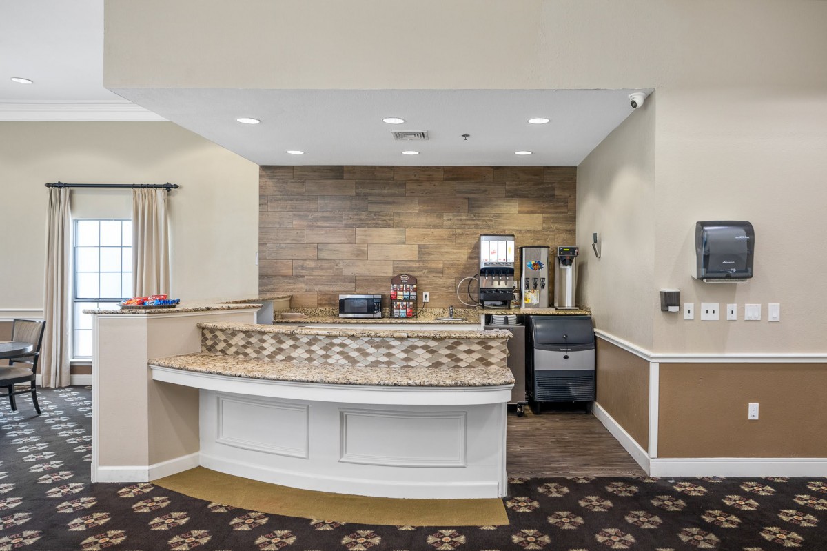 A hotel breakfast area with a coffee station and beverage machines.