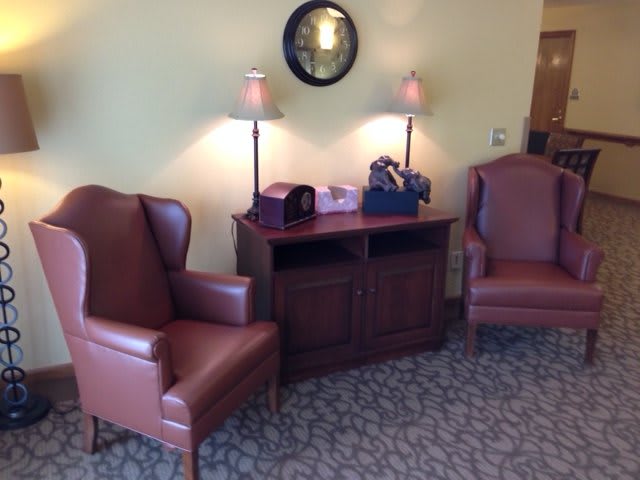 A cozy seating area with two leather chairs, a wooden table, and lamps.