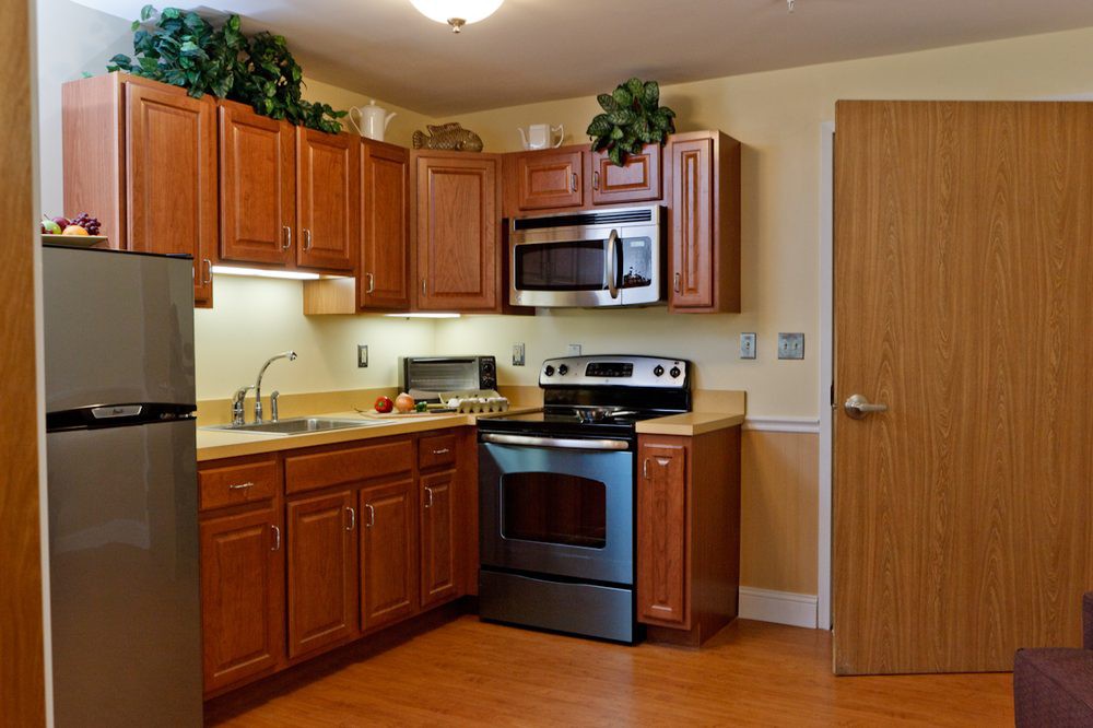 A modern kitchen with wooden cabinets, stainless steel appliances, and a wooden floor.