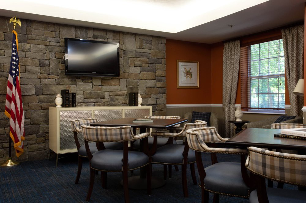 A cozy dining area with tables, chairs, a wall-mounted television, and a stone accent wall.