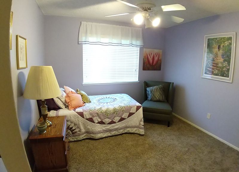 A cozy bedroom with a single bed, armchair, and decorative elements.