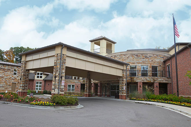 A view of a modern building entrance with stone and brick architecture under a cloudy sky.