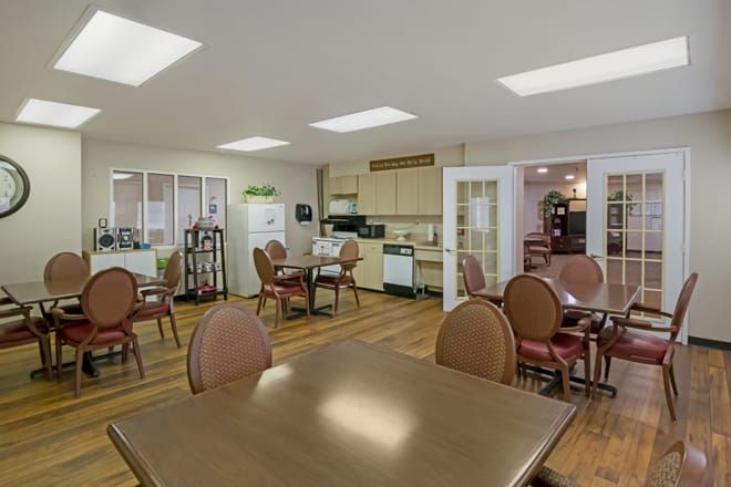 A cozy dining area with multiple tables and chairs, adjacent to a small kitchen.